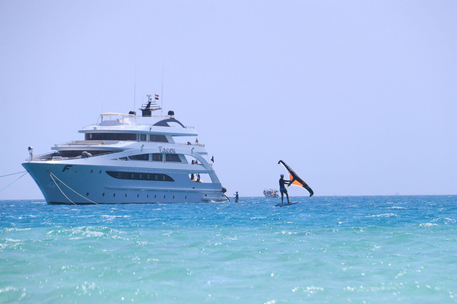 Een winger vaart weg van een voor anker liggend liveaboard jacht in de Rode Zee